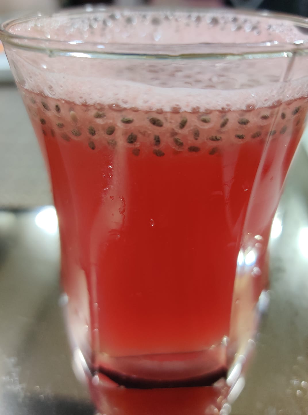 A glass of watermelon juice with puffed chia seeds at the brim